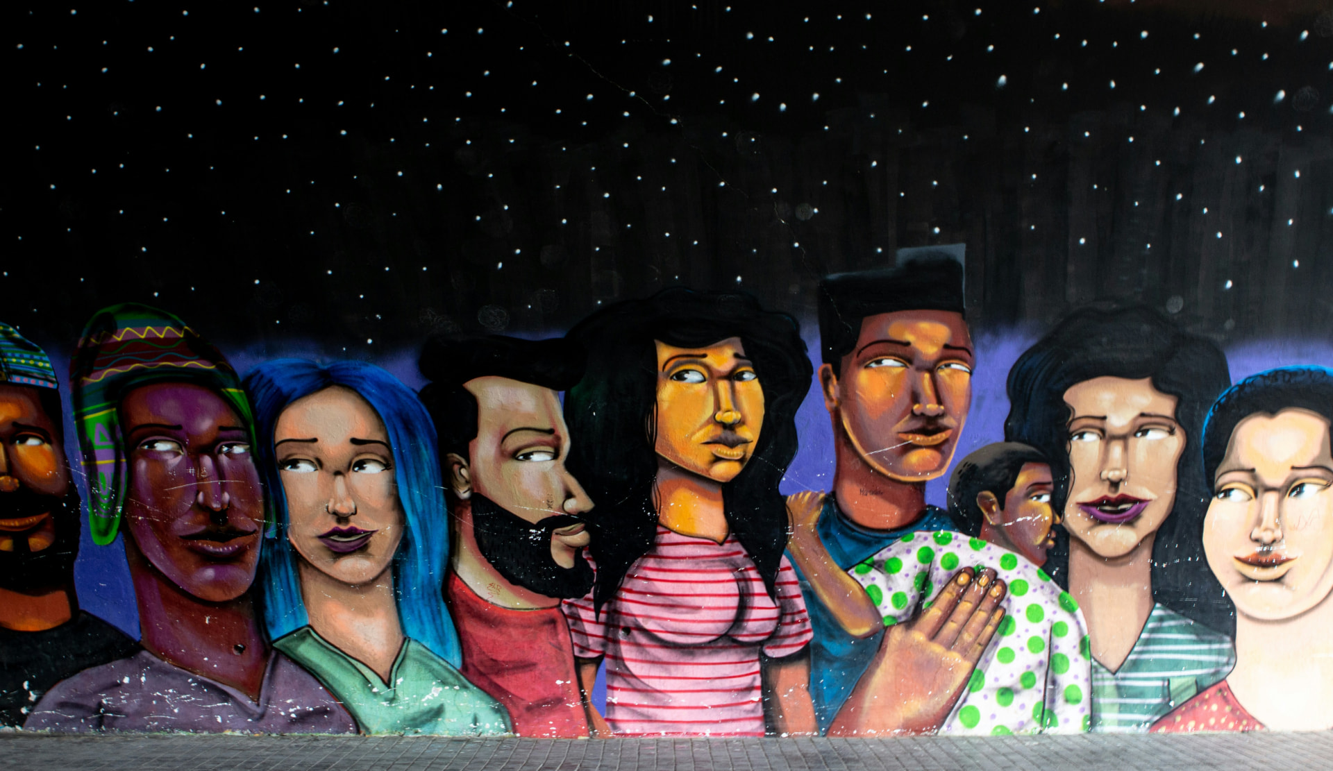 Street mural of a diverse crowd of young people beneath a starry night sky